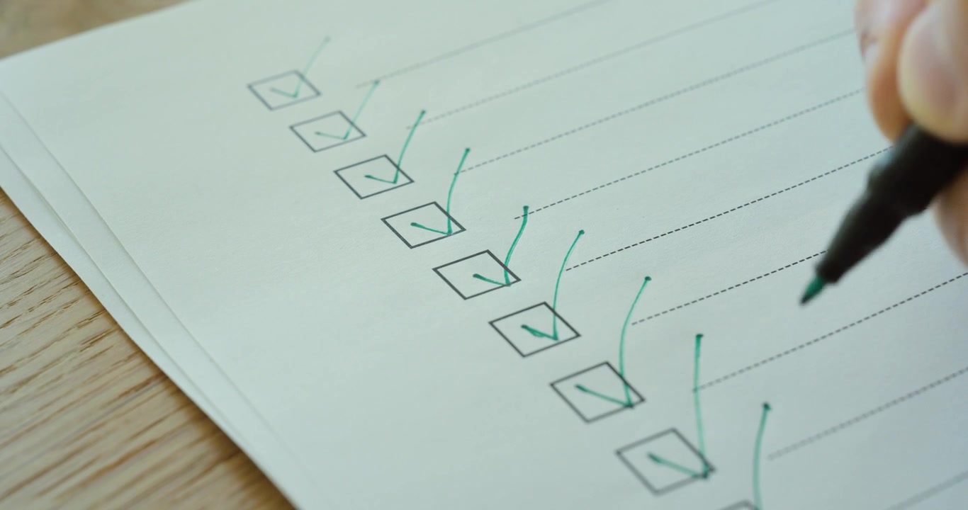 Close-up of a person marking checkboxes on a checklist, representing productivity, organization, and task completion.