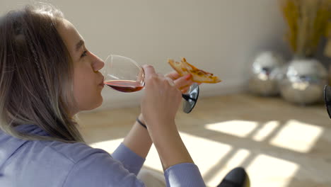 primo piano di due ragazze felici che tostano con vino e condividono la pizza a casa