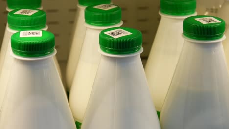 close-up of many beautiful bottles of diary product with green caps and a male buyer takes one