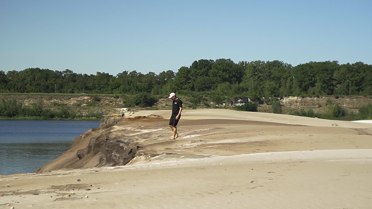 hombre hispano caminando por el lago de la playa en el bosque belga y revisando la arena cuidadosamente