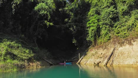 man on his kayak floating on the water on the calm lake in ratchaprapa dam, khao sok national park, thailand