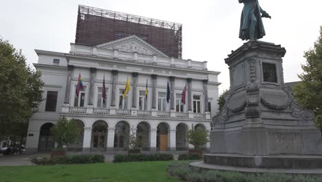 the opéra royal de wallonie, located in liège, belgium, showcasing elaborate architecture and a statue in the foreground. flags decorate the building