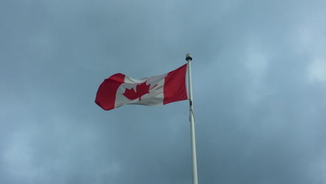 slow-motion: red and white canadian flag waving against a cloudy sky