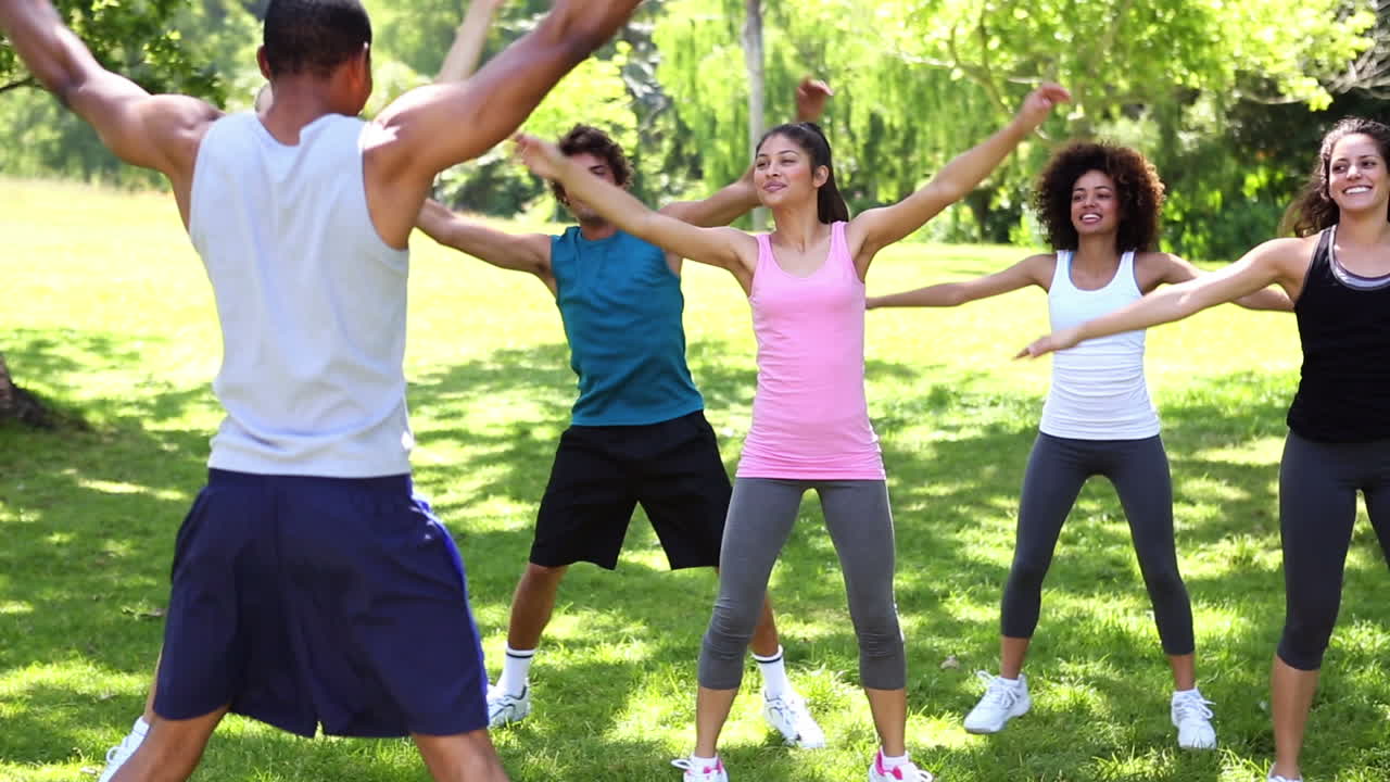 Premium stock video Fitness class doing jumping jacks in the park