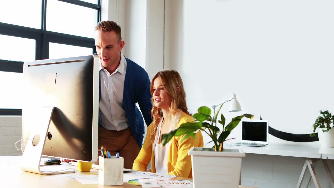 Forretningskvinde med mand, mens de arbejder på computer