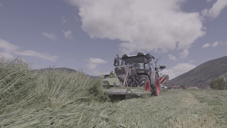 Trattore che taglia l'erba in un prato, moderna attrezzatura agricola automatizzata