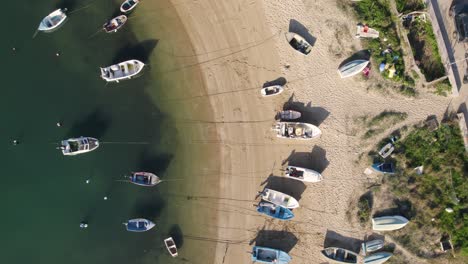 aerial top down forward over many fisher boats docked on sand beach