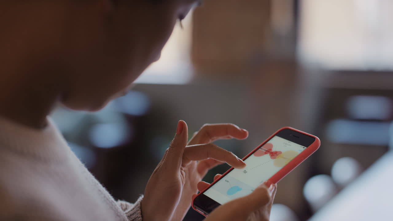 cerca de las manos de las mujeres usando el teléfono inteligente para leer gráficos de negocios