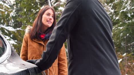 Pareja-Hablando-Mientras-Carga-El-Coche-Eléctrico-En-Un-Día-Nevado