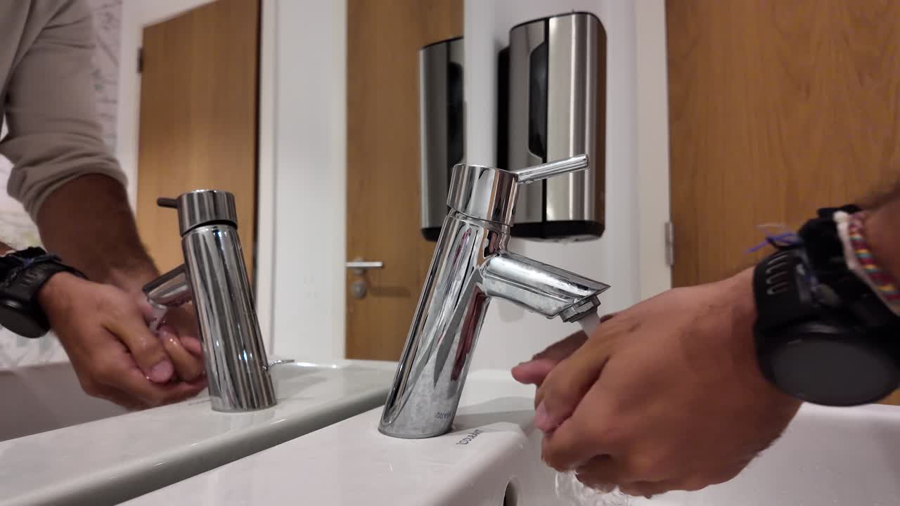Slow motion hands being washed with soap and water in a modern bathroom