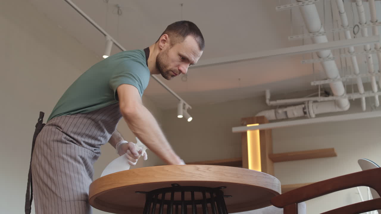 Man Cleaning Table in Cafe