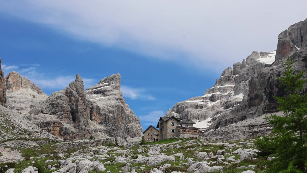 Berghütte Tuckett, Brenta-Dolomiten-Gipfel mit Schneeflecken und einer felsigen Almwiese.