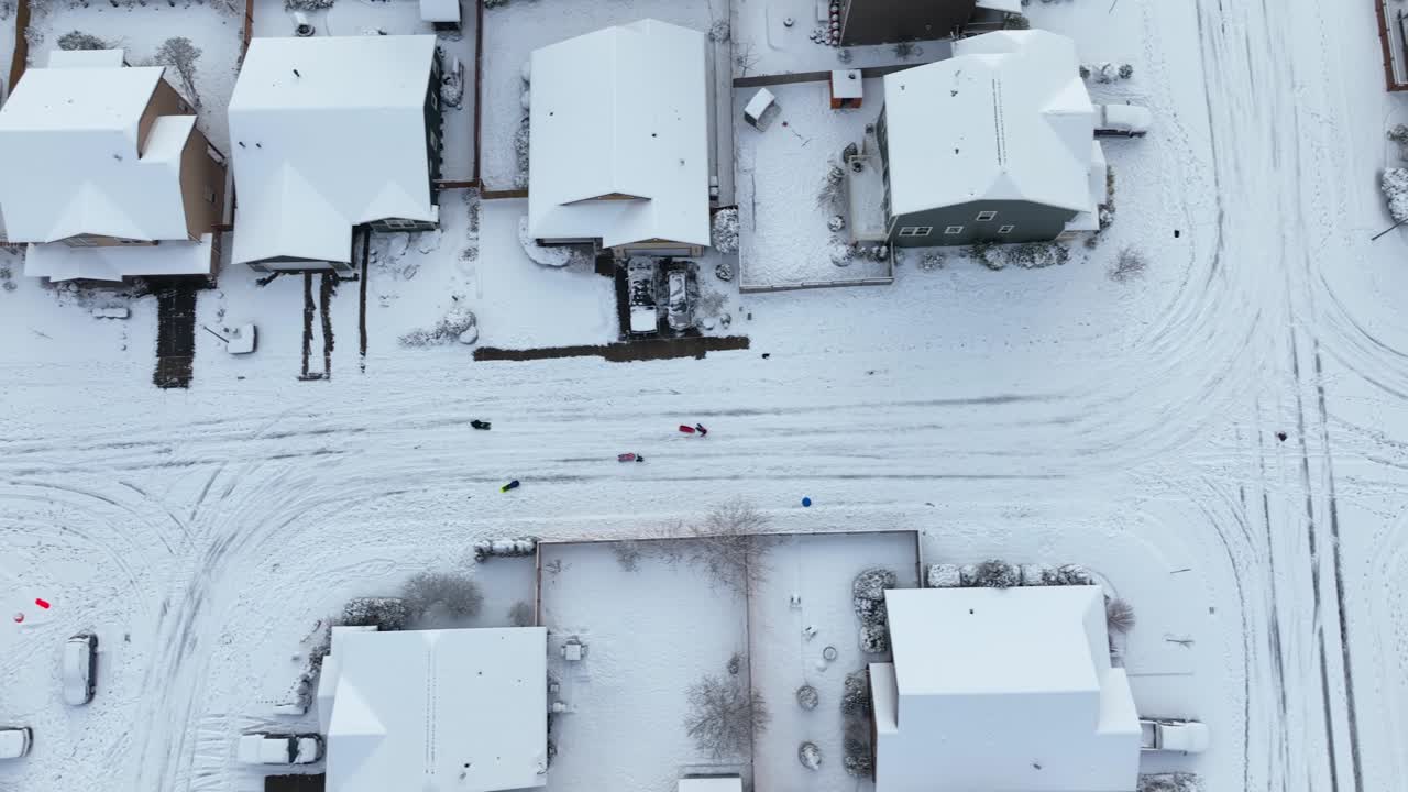 vista aérea de arriba hacia abajo de niños jugando en calles cubiertas de nieve