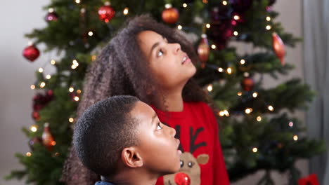 children watching game of charades with christmas tree in background