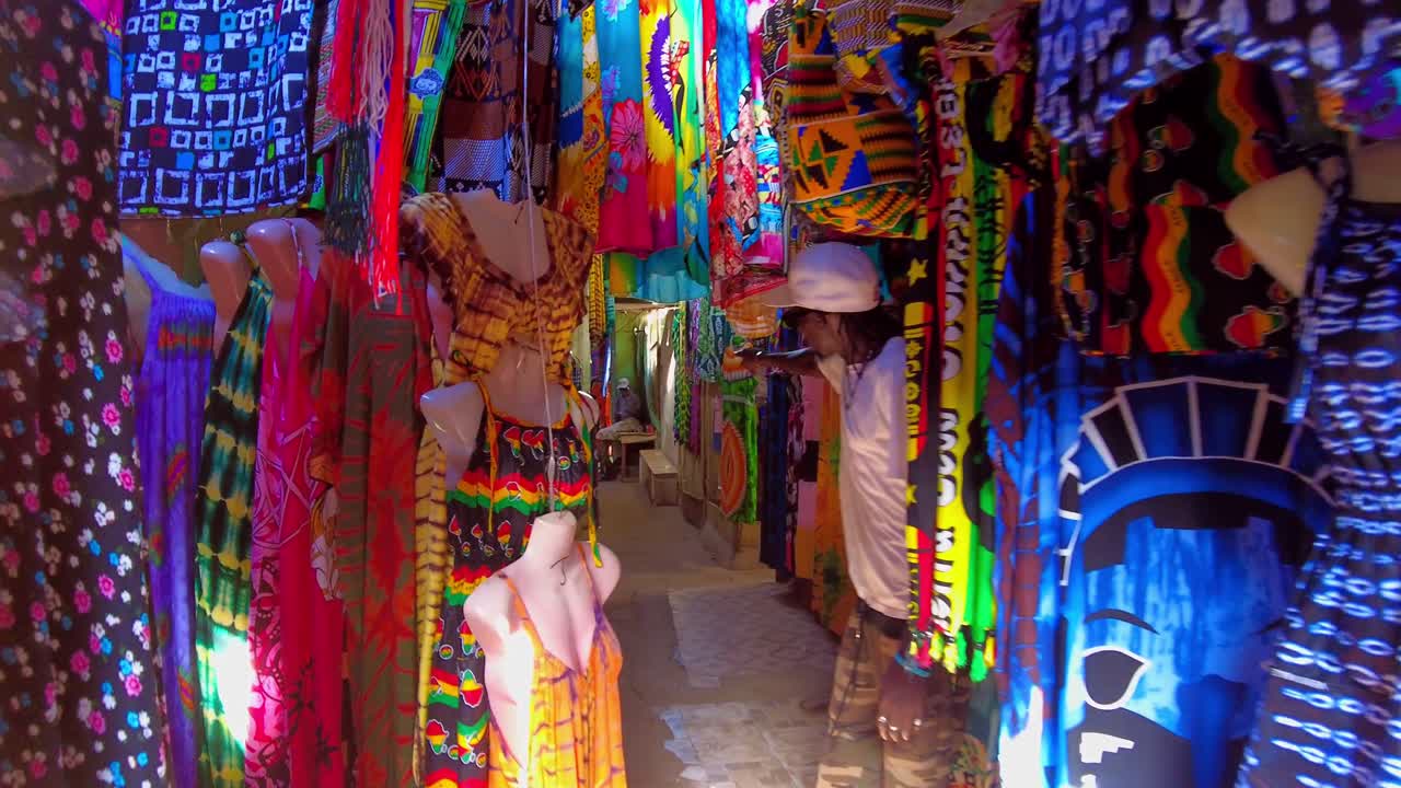 POV shot following a man walking in middle of clothes at the Serekunda market