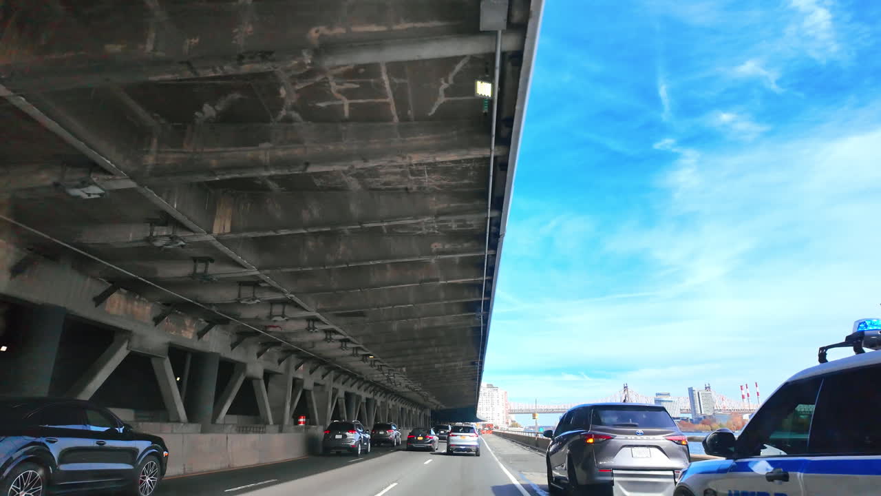 2026年4月1日、アメリカ合衆国ニューヨーク：マンハッタンのイーストリバー沿いFDRドライブの高速道路交通。背景にクイーンズボロ橋を望むFDRドライブの高架下を走行する車。