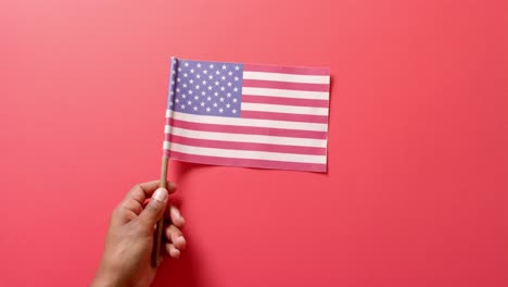 close up of hand holding national flag of usa on red background