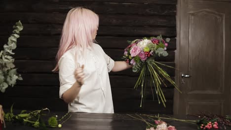 professional florist in white shirt decorates a fashionable bouquet complementing with flowers for the perfect composition. oncoming