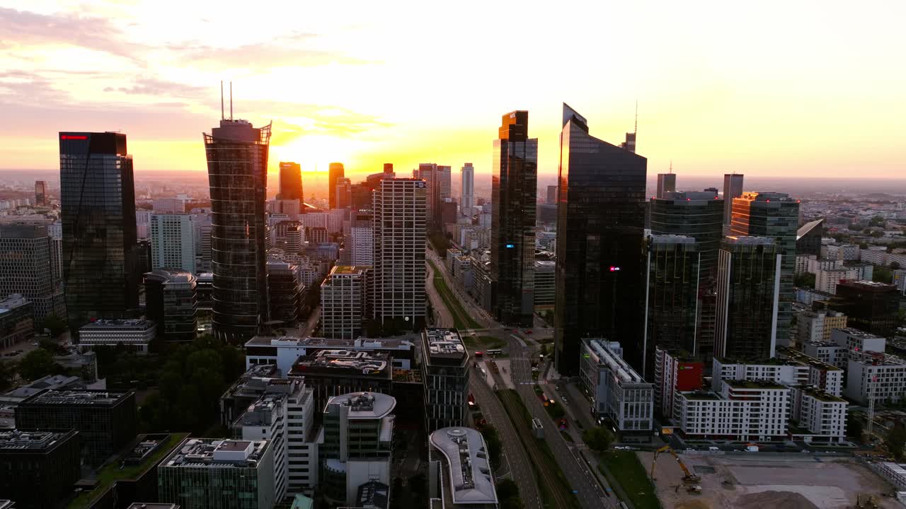 Drone flight, Warsaw towers lighting up as sunrise spreads across city horizon
