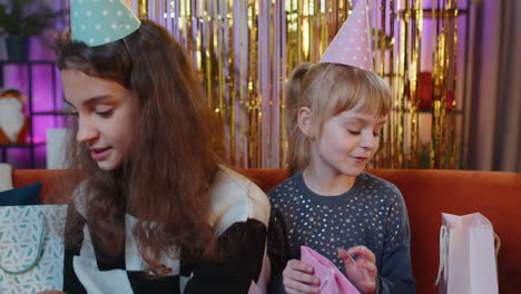 happy siblings children girls celebrating birthday party with many gift presents surprise at home