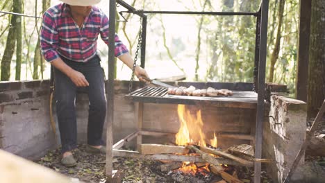 Ethnic-man-preparing-raw-meat-pieces-above-burning-fire