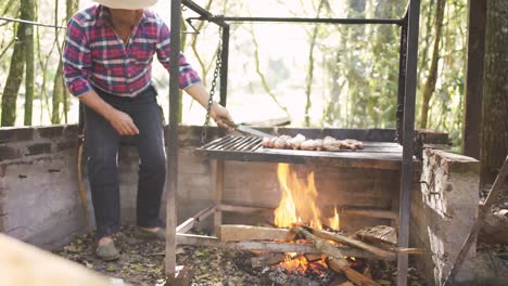 hombre étnico preparando trozos de carne cruda sobre un fuego ardiente