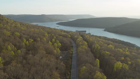 Aerial-footage-of-a-road-in-the-forest-on-a-mountain-with-Nickjack-Lake-Tennessee-in-the-background