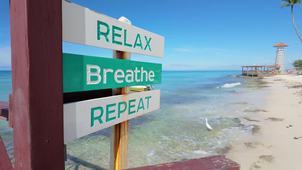 Relax, Breathe, Repeat sign and lighthouse at Dominicus Beach, Dominican Republic. Static view