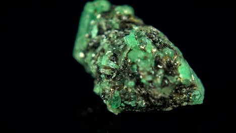 la rotación sin problemas de un mineral verde (esmeralda) frente a un fondo negro