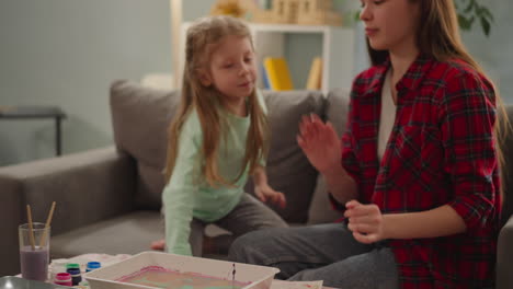 sisters finish eggs coloring and give high five at home