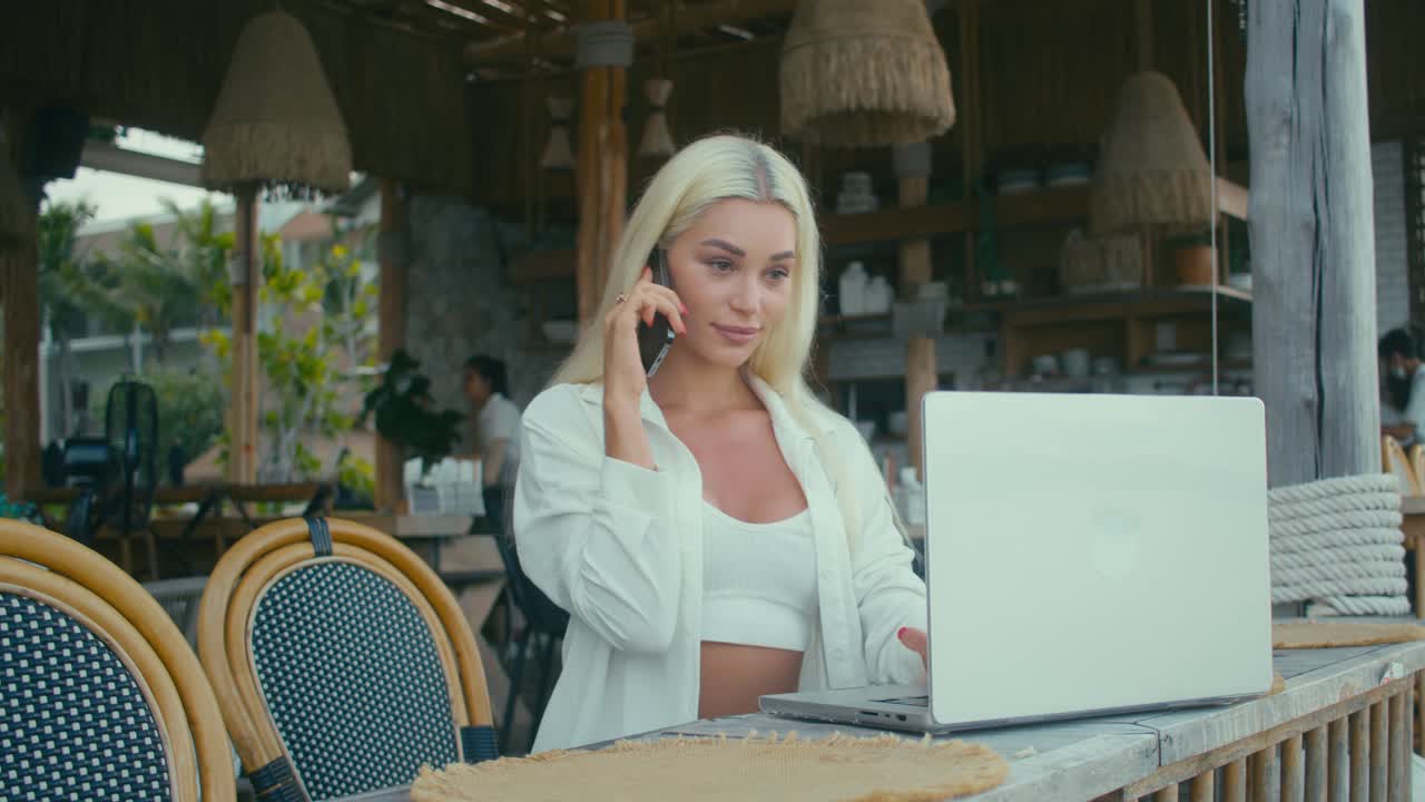 Kvinde arbejder udendørs på strandcafé.