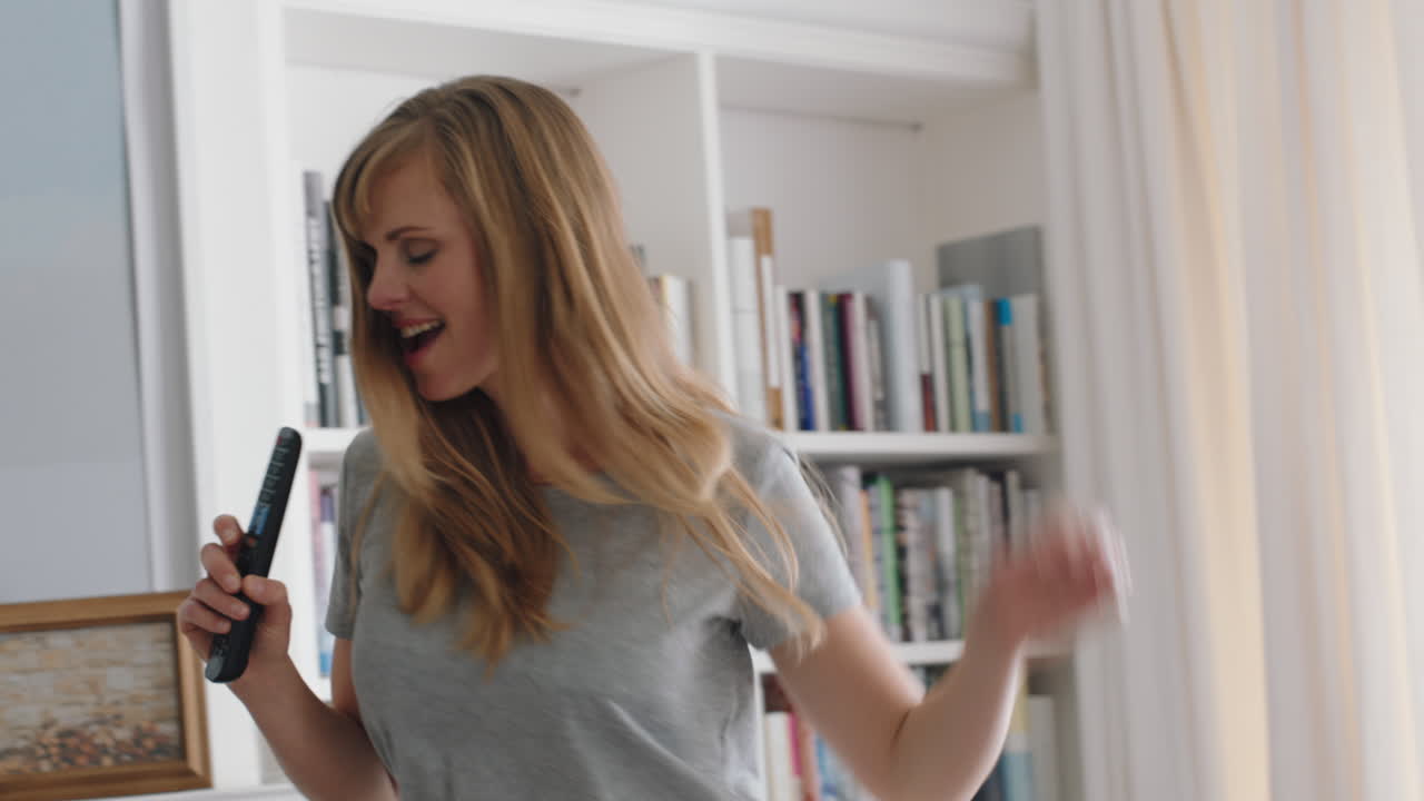 happy woman singing karaoke at home having fun dancing to music celebrating success enjoying funny dance feeling positive lifestyle achievement 4k footage