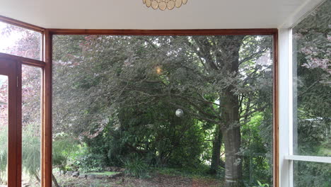 Static-shot-featuring-a-sitting-room,-with-a-tree-gently-blowing-in-the-wind