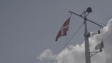danish flag waving in the wind in slowmotion hanging from a boat in copenhagen denmarkt log