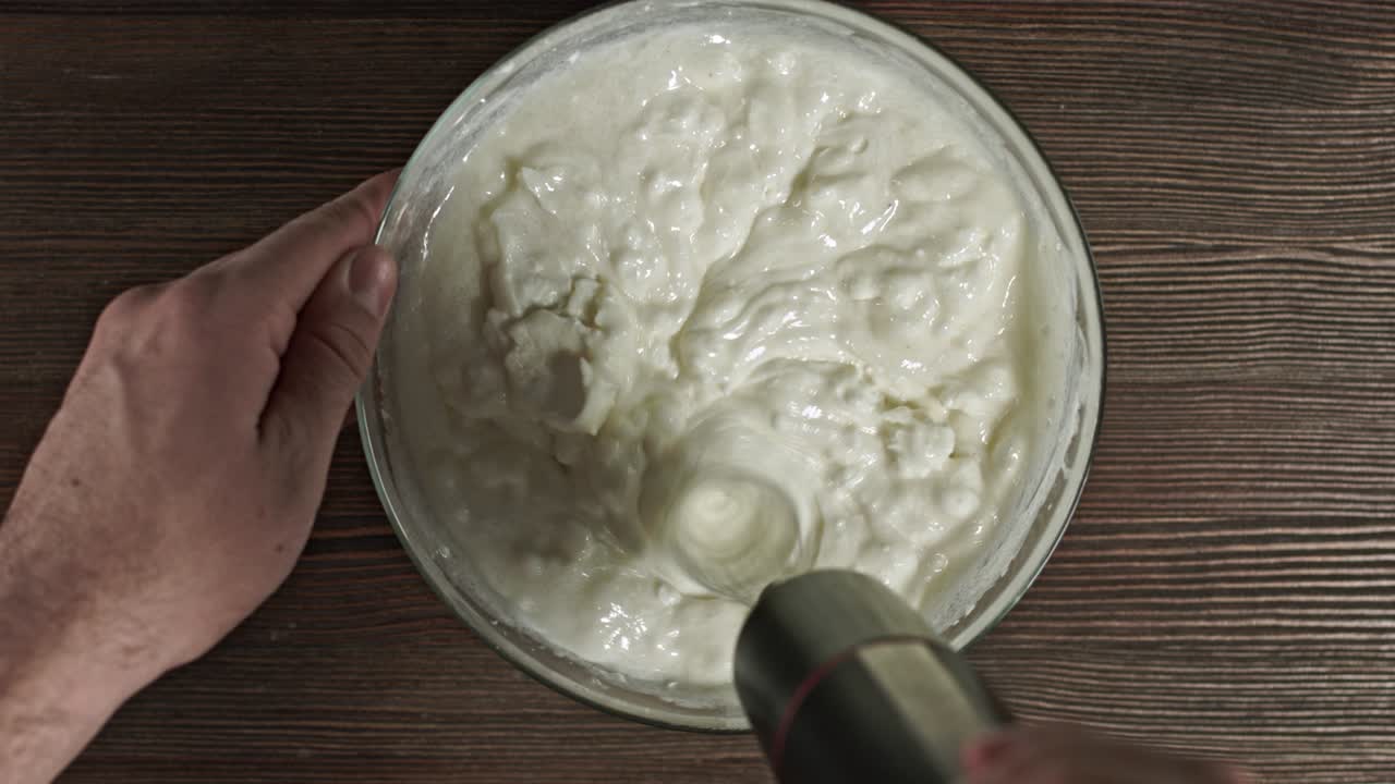 Add ingredients to a glass bowl. Male hands making dessert. Delicious soft sour cream cheese sweet cream. Kneading the ingredients. Fresh natural homemade yogurt. Stuffing for eclairs. Curd dessert.