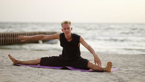 un joven practica yoga en una alfombra deportiva durante el amanecer del hijo. haciendo un ejercicio específico. estirando el cuerpo. ocio