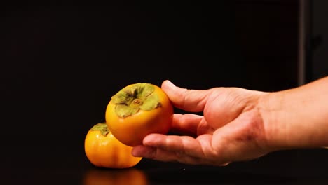 una mano recoge y sostiene persimmonas