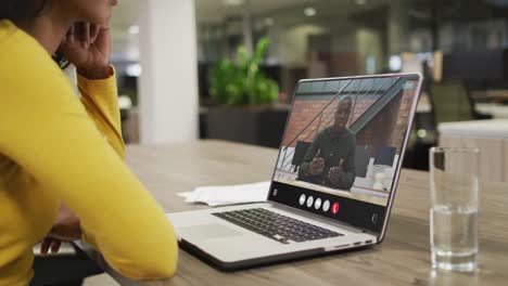 Mujer-Birracial-Usando-Una-Computadora-Portátil-Para-Videollamada,-Con-Un-Colega-De-Negocios-En-La-Pantalla