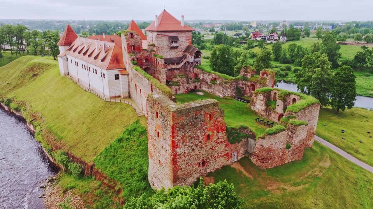 Drone si innalza sopra la fortezza medievale di Bauska e i verdi pendii rivieraschi