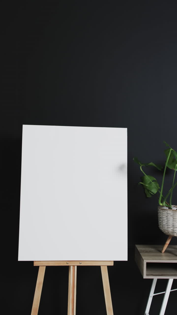 Vertical video of white canvas sign on wooden easel with copy space on black background