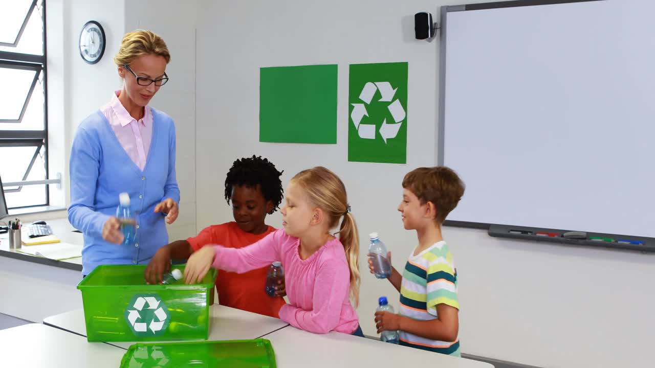 School kids putting bottle in recycle logo box in classroom