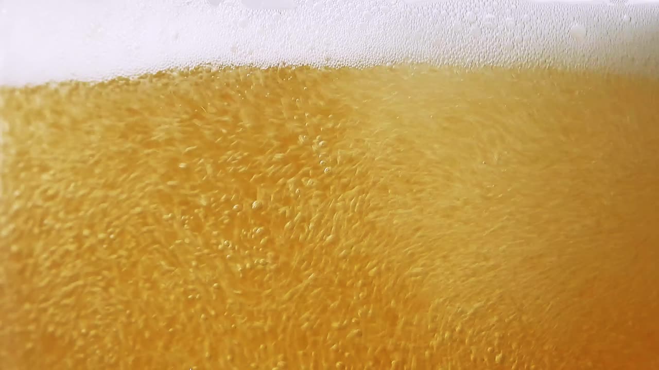 la cerveza se vierte en el vaso y las burbujas forman espuma