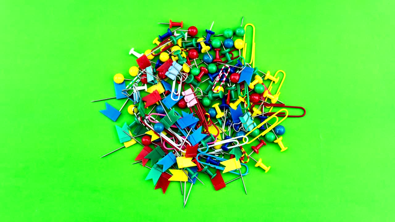 4-k lapso de tiempo de un conjunto de coloridos alfileres de color pulso thumbtacks en fondo de papel verde