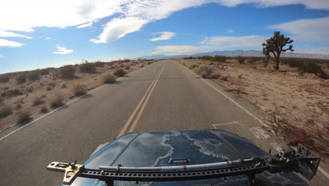 pov racing down beat up weathered road in mojave desert landscape