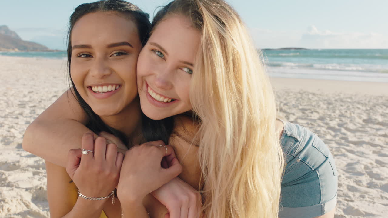 해변에서 여자 친구를 안아주는 젊은 여성 놀라운 안아주는 최고의 친구들이 즐거운 여름 휴가를 보내고 있습니다.