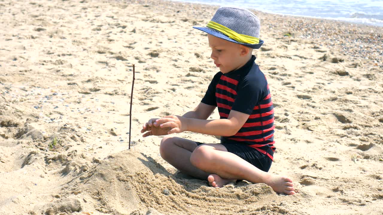 장난감으로 놀고 해변에 모래 성을 짓는 재미있는 소년.
