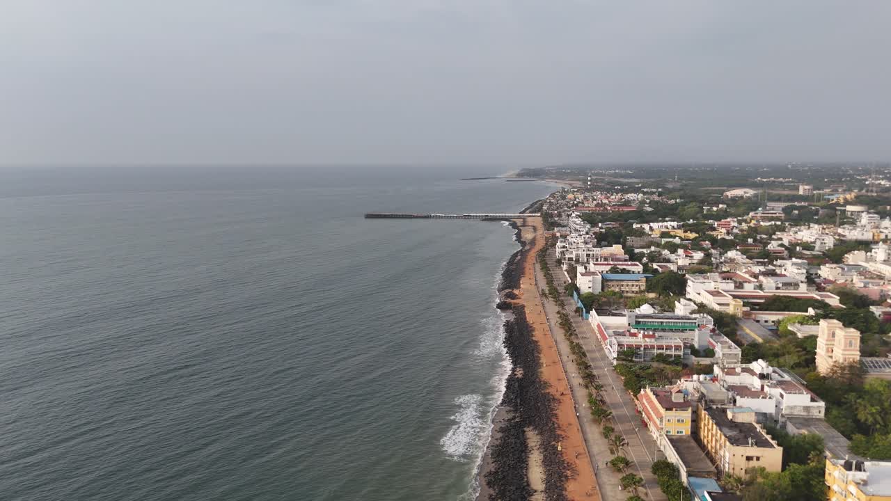 Sorvolo sereno con drone che cattura il contrasto tra edifici cittadini e mare tranquillo