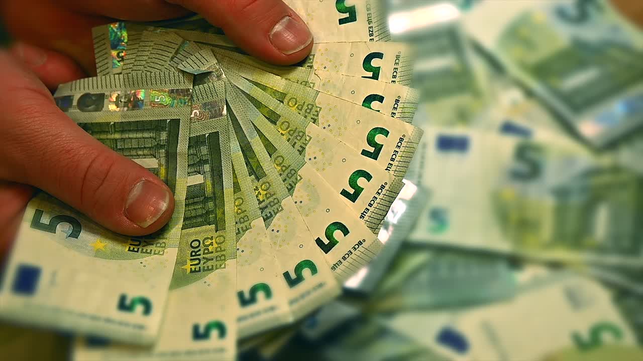 manos blancas clasificando eficientemente a través de un montón de billetes de 5 euros, primer plano