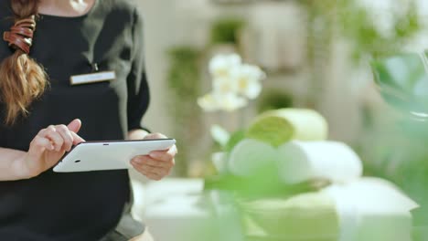smiling woman employee in modern beauty salon using tablet pc