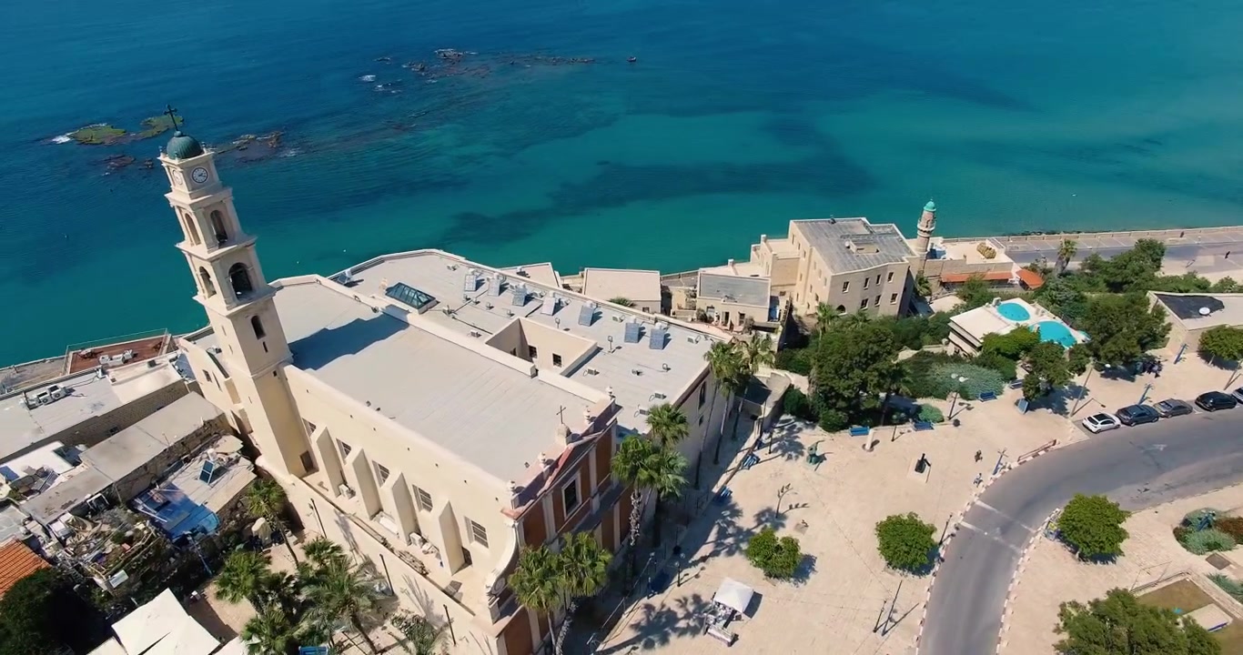 Tomada aérea orbital da Igreja de São Pedro na Antiga Jaffa, Israel. Litoral mediterrâneo, mar turquesa, arquitetura histórica e paisagem à beira-mar capturados por drone.